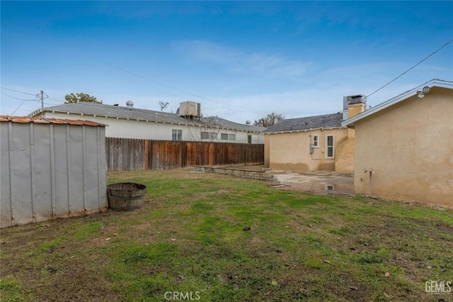 view of yard with an outbuilding, a patio area, a fenced backyard, and a shed