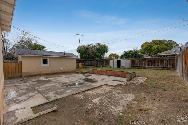 view of yard with an outbuilding, a patio area, a fenced backyard, and a storage shed