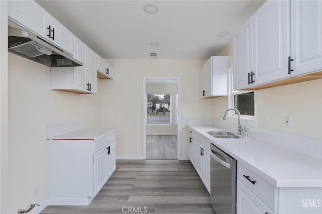 kitchen with light countertops, stainless steel dishwasher, white cabinets, a sink, and under cabinet range hood