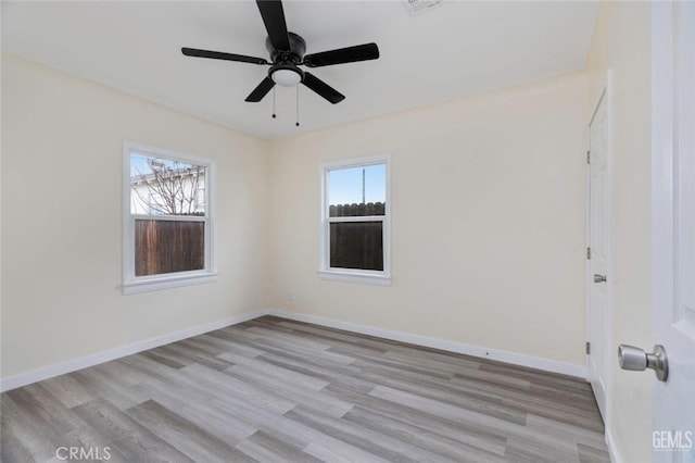 empty room with a ceiling fan, light wood-type flooring, and baseboards