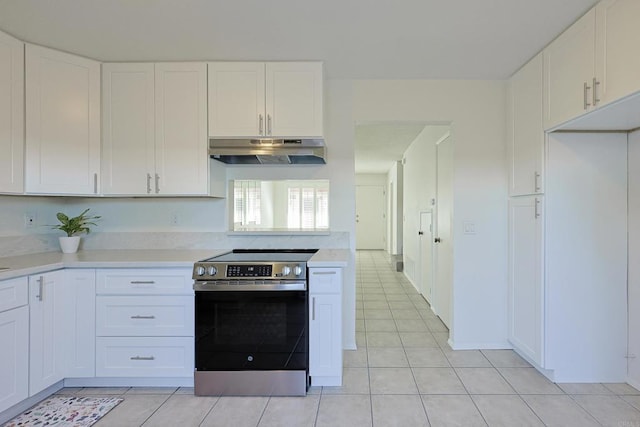 kitchen featuring light tile patterned floors, light countertops, white cabinetry, under cabinet range hood, and stainless steel electric range