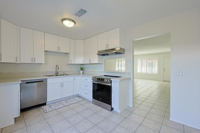 kitchen with under cabinet range hood, appliances with stainless steel finishes, light countertops, and a sink