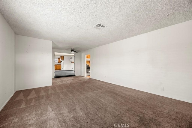 unfurnished living room with ceiling fan, visible vents, dark colored carpet, and a textured ceiling