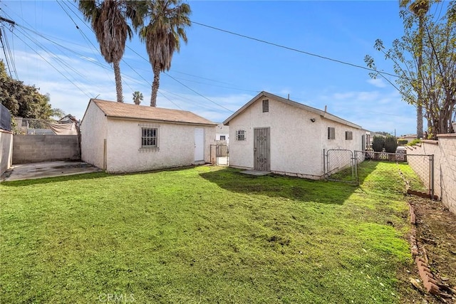 back of property with a fenced backyard, a yard, and stucco siding