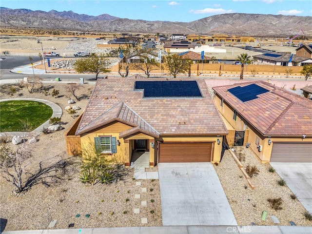 view of front of property featuring an attached garage, a mountain view, driveway, roof mounted solar panels, and stucco siding