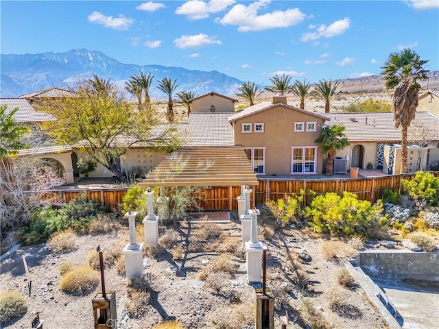 view of front of home with a tile roof, a mountain view, fence, and stucco siding