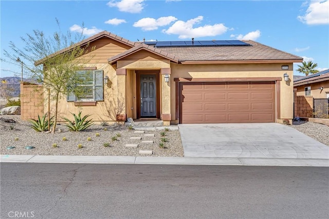 single story home featuring a garage, concrete driveway, a tiled roof, roof mounted solar panels, and stucco siding