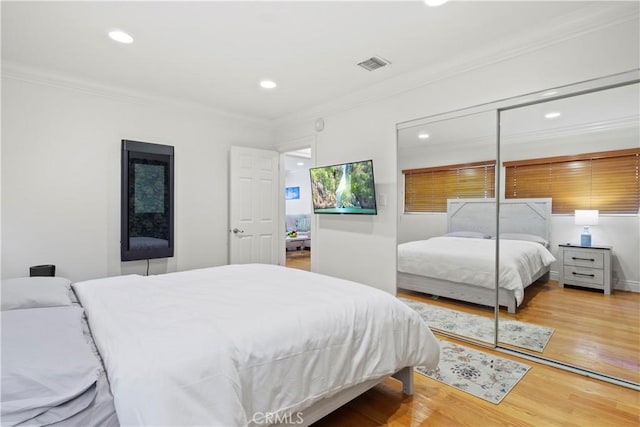 bedroom featuring ornamental molding, a closet, visible vents, and wood finished floors