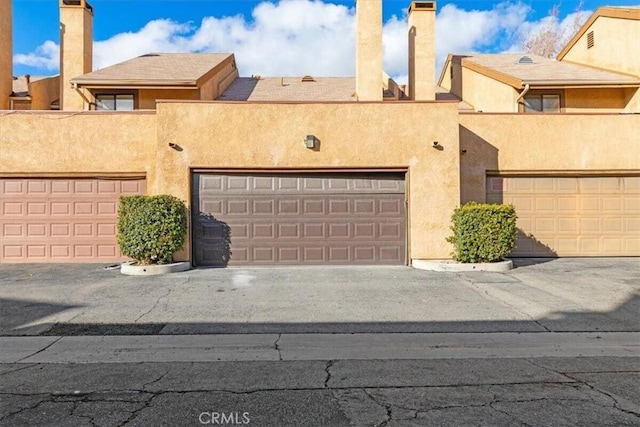 exterior space featuring a garage, a chimney, and stucco siding