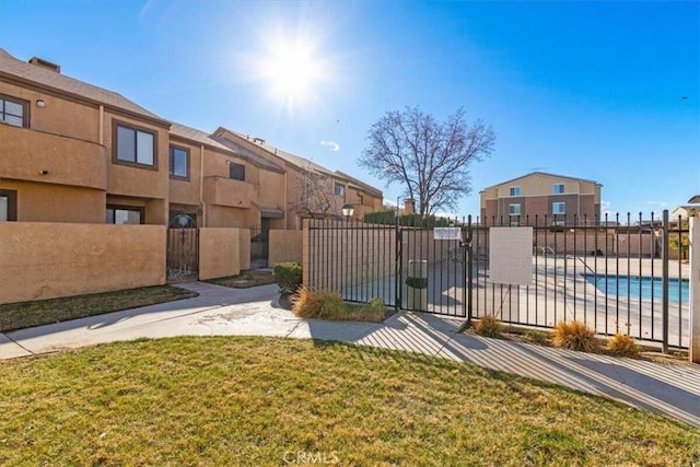 view of property's community featuring a yard, a gate, fence, and a swimming pool