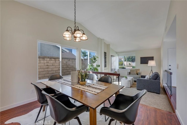 dining space featuring lofted ceiling, baseboards, a chandelier, and wood finished floors