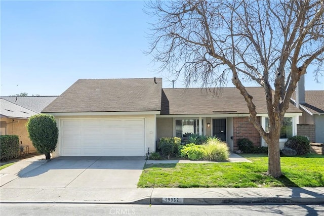 ranch-style home with a garage, concrete driveway, stucco siding, a front yard, and brick siding