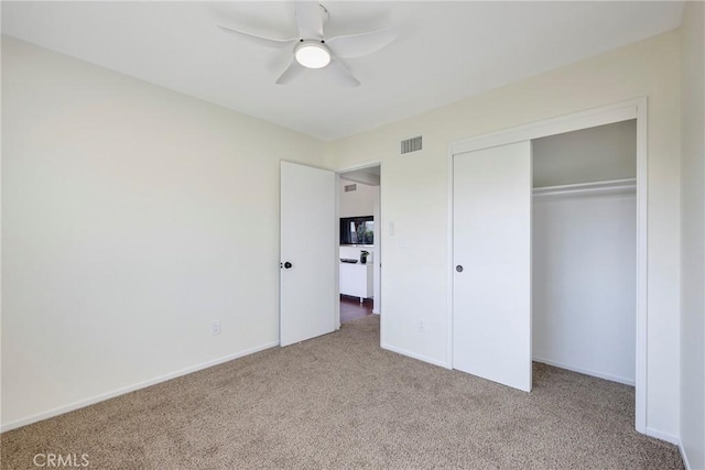 unfurnished bedroom with baseboards, visible vents, a ceiling fan, light colored carpet, and a closet