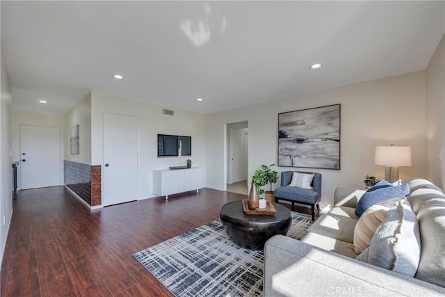 living room featuring dark wood-style flooring, visible vents, and recessed lighting