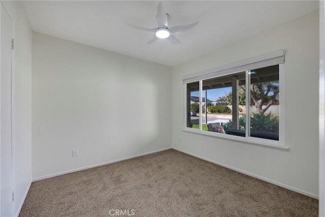 carpeted spare room featuring a ceiling fan and baseboards