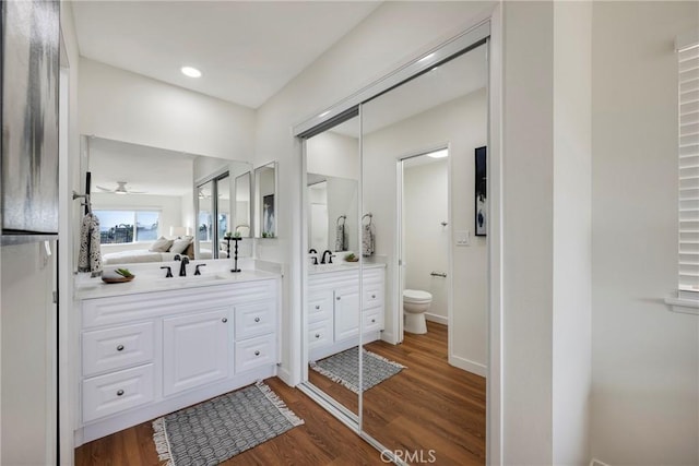 ensuite bathroom featuring a ceiling fan, toilet, wood finished floors, ensuite bathroom, and vanity