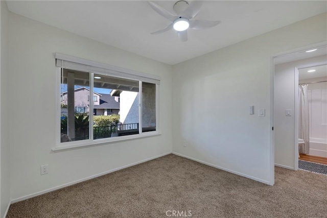 carpeted empty room with ceiling fan and baseboards