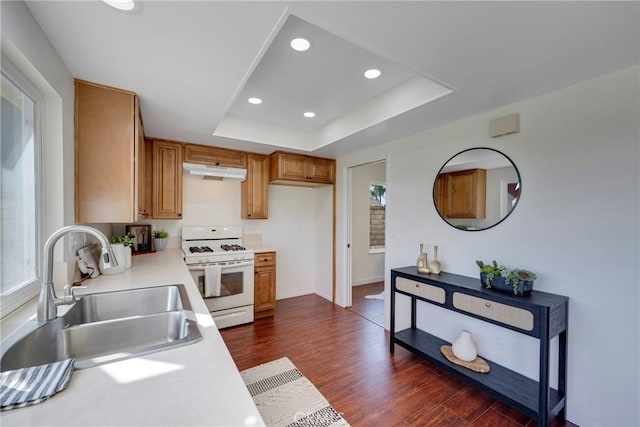 kitchen featuring under cabinet range hood, a sink, white range with gas cooktop, light countertops, and a tray ceiling