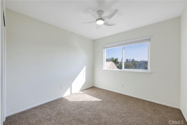 carpeted spare room featuring ceiling fan and baseboards