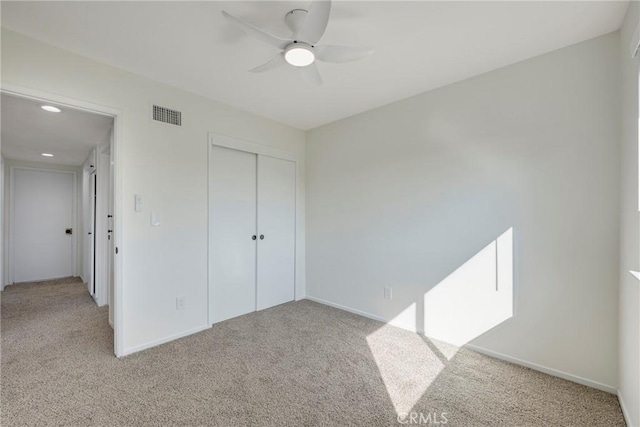 unfurnished bedroom with baseboards, a closet, visible vents, and light colored carpet