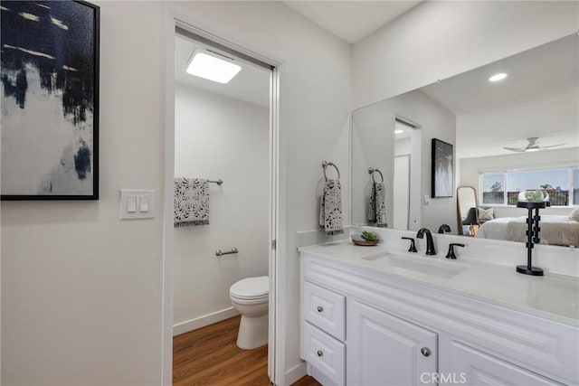 full bath with baseboards, a ceiling fan, toilet, wood finished floors, and vanity