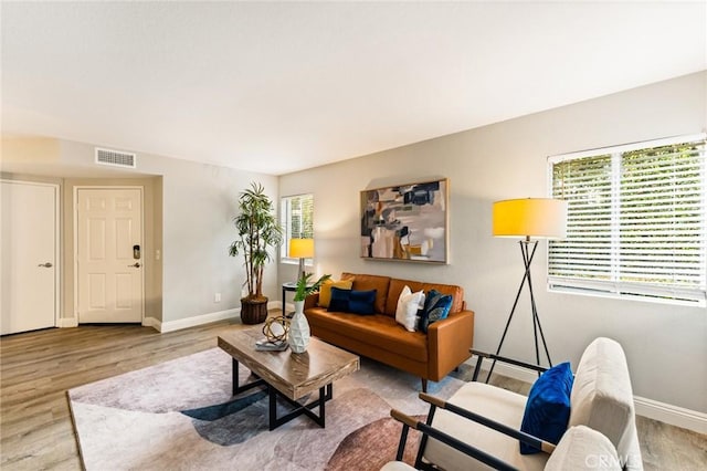 living area with wood finished floors, visible vents, and baseboards