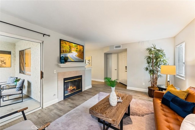 living room featuring baseboards, a fireplace, visible vents, and wood finished floors