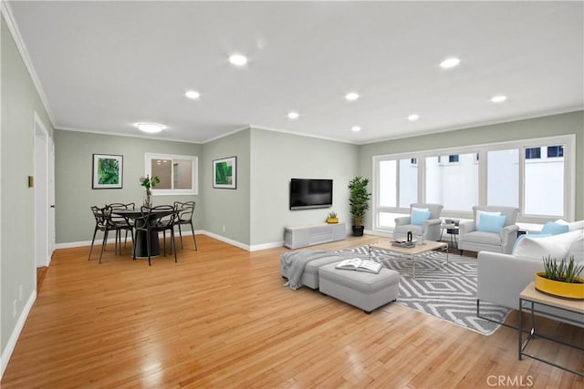 living area featuring ornamental molding, light wood-type flooring, and baseboards