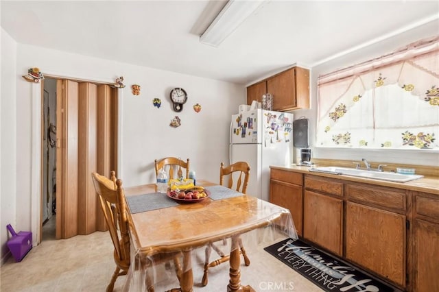 kitchen featuring a sink, brown cabinetry, light countertops, and freestanding refrigerator