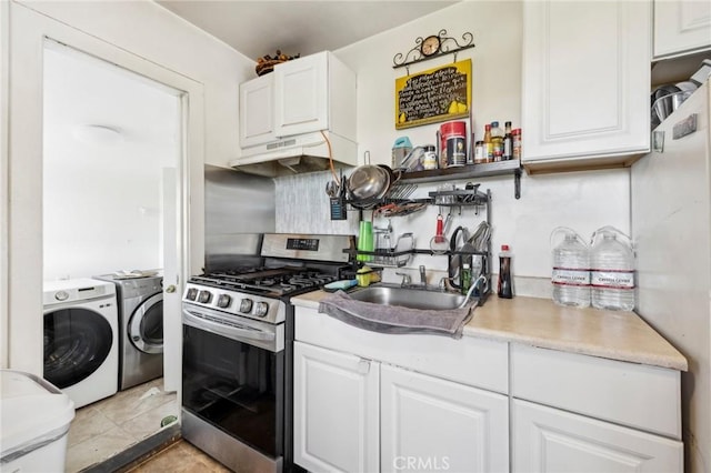 kitchen with under cabinet range hood, white cabinets, light countertops, independent washer and dryer, and stainless steel range with gas cooktop