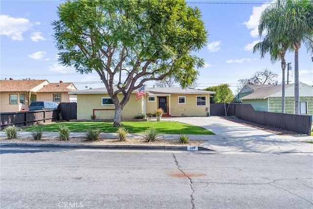 ranch-style home featuring driveway, a front yard, fence, and stucco siding