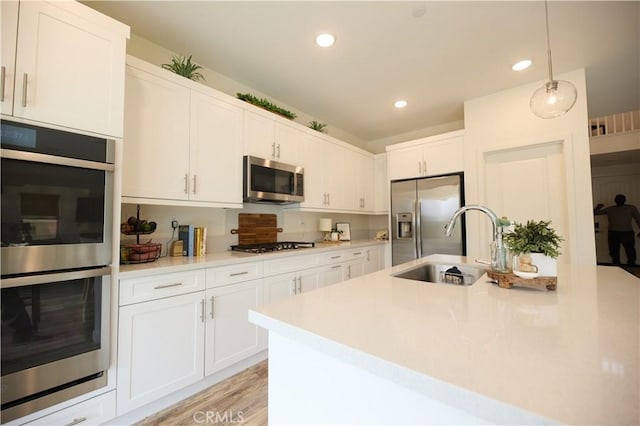 kitchen featuring stainless steel appliances, pendant lighting, light countertops, and white cabinetry