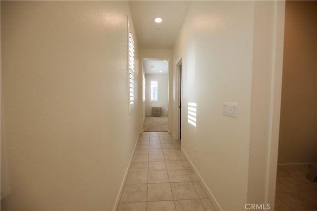 hall featuring recessed lighting, baseboards, and light tile patterned flooring