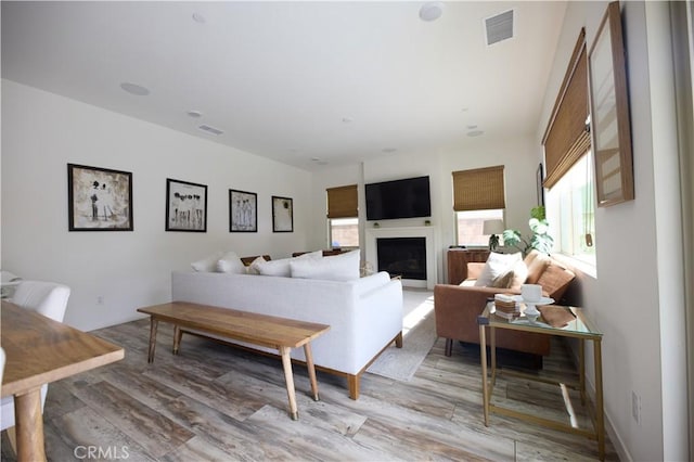 living area featuring light wood-style flooring, a fireplace, and visible vents