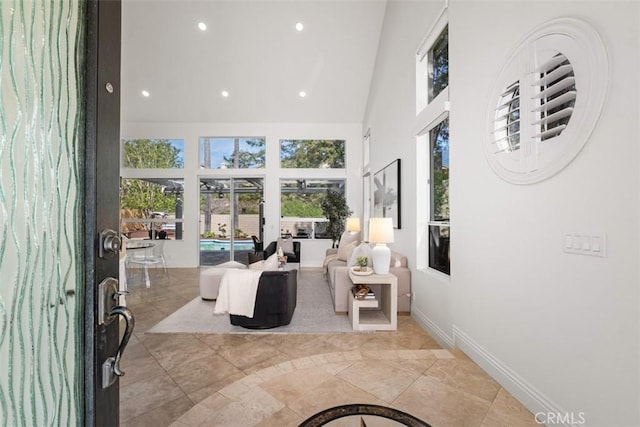 interior space featuring a high ceiling, recessed lighting, and baseboards