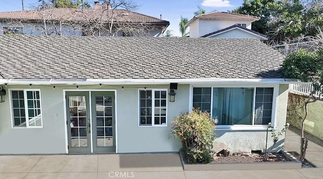 rear view of house featuring a shingled roof and stucco siding