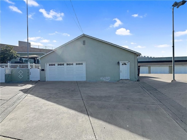 garage with concrete driveway and fence