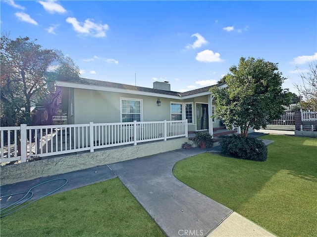 ranch-style house featuring a front yard, fence, and stucco siding