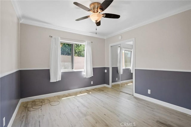 spare room with light wood finished floors, baseboards, ornamental molding, and a ceiling fan