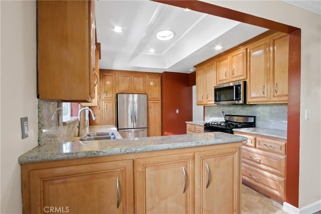 kitchen featuring stainless steel appliances, a peninsula, a sink, and light stone countertops