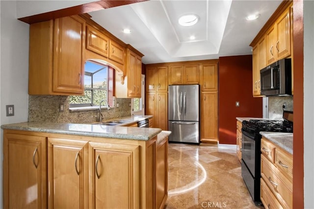 kitchen featuring a tray ceiling, backsplash, a sink, a peninsula, and black appliances