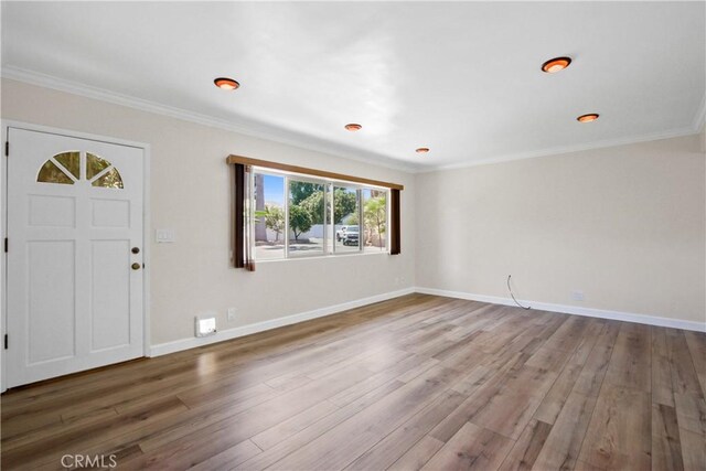 foyer entrance with crown molding, wood finished floors, and baseboards