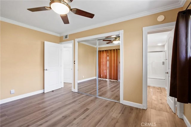 unfurnished bedroom featuring light wood-type flooring, baseboards, and crown molding