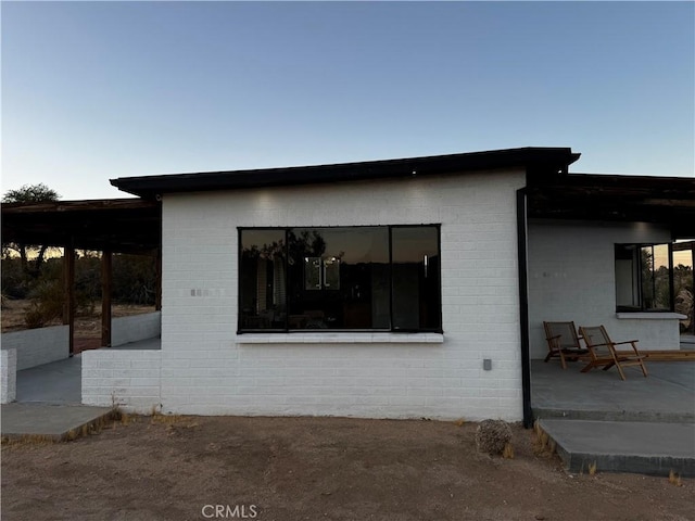 view of property exterior with brick siding and a patio