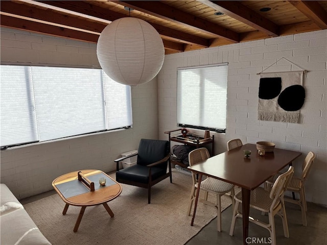 dining space featuring beam ceiling, concrete floors, wooden ceiling, and concrete block wall