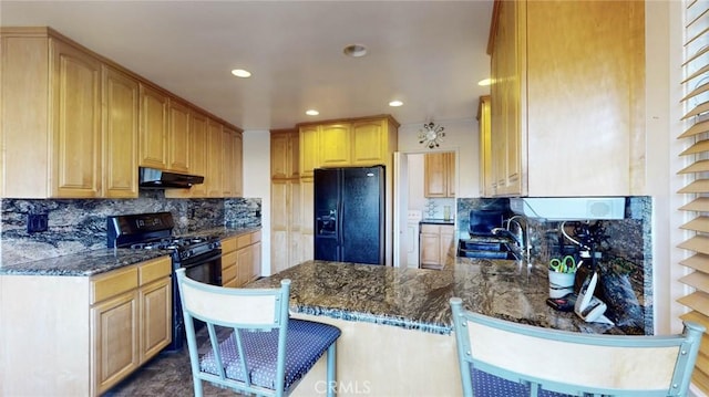 kitchen featuring a sink, black appliances, a peninsula, under cabinet range hood, and a kitchen breakfast bar