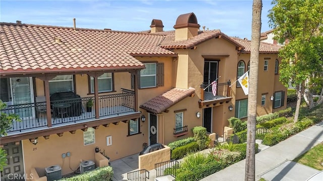 exterior space with a chimney, stucco siding, cooling unit, and a tile roof