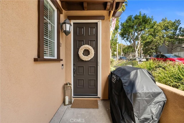 property entrance featuring a balcony and stucco siding