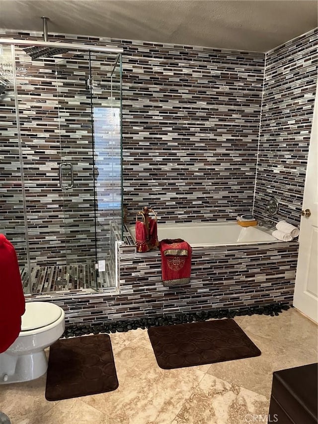 bathroom featuring toilet, tiled tub, and a textured ceiling