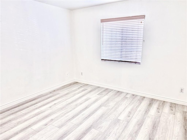 spare room with baseboards and wood finished floors